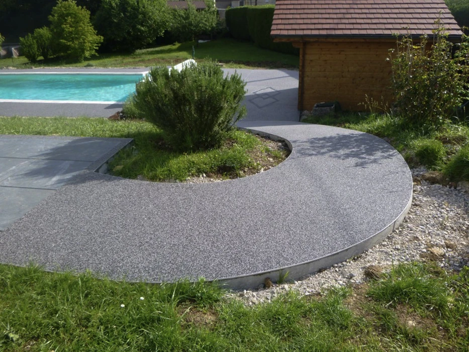 Aménagement paysager extérieur résidentiel avec allée piétonne courbe en béton désactivé gris