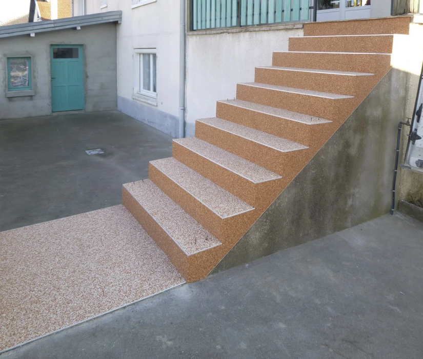 Escalier extérieur en béton avec revêtement granulat apparent orange-brun, contremarches et nez de marches blancs