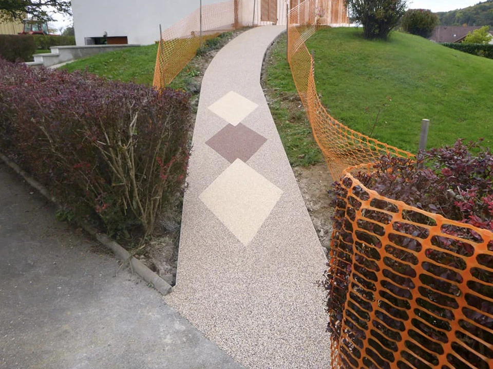 Terrasse extérieure en béton désactivé beige avec motif décoratif géométrique